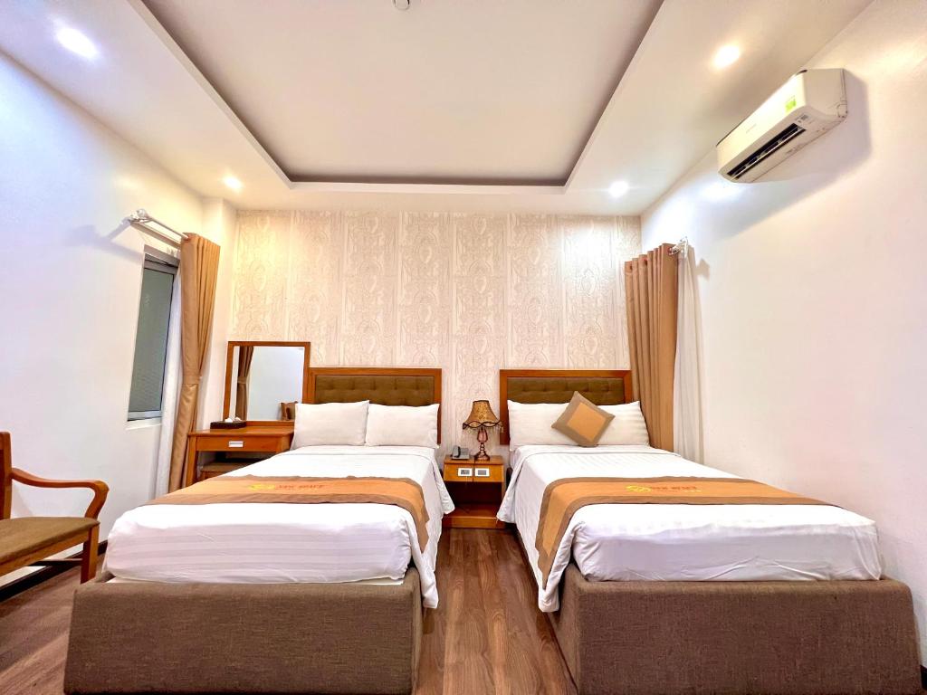 two beds in a hotel room with two bedsitures at New Space Hotel Airport in Ho Chi Minh City