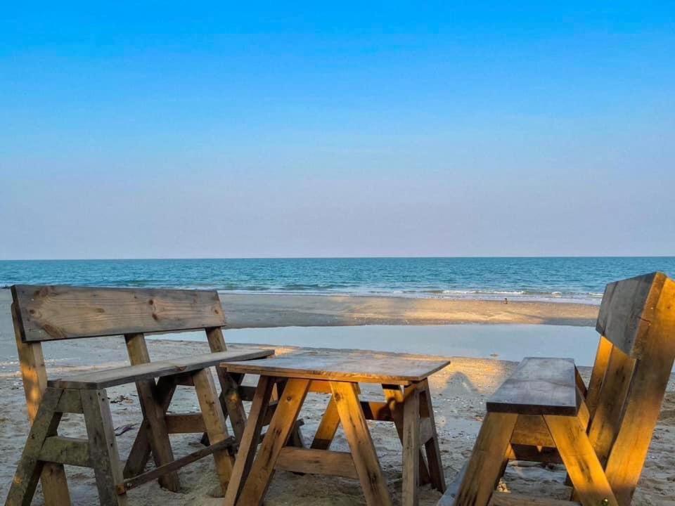 Loongmun Beach في تشا أم: طاولة خشبية و كرسيين للجلوس على الشاطئ