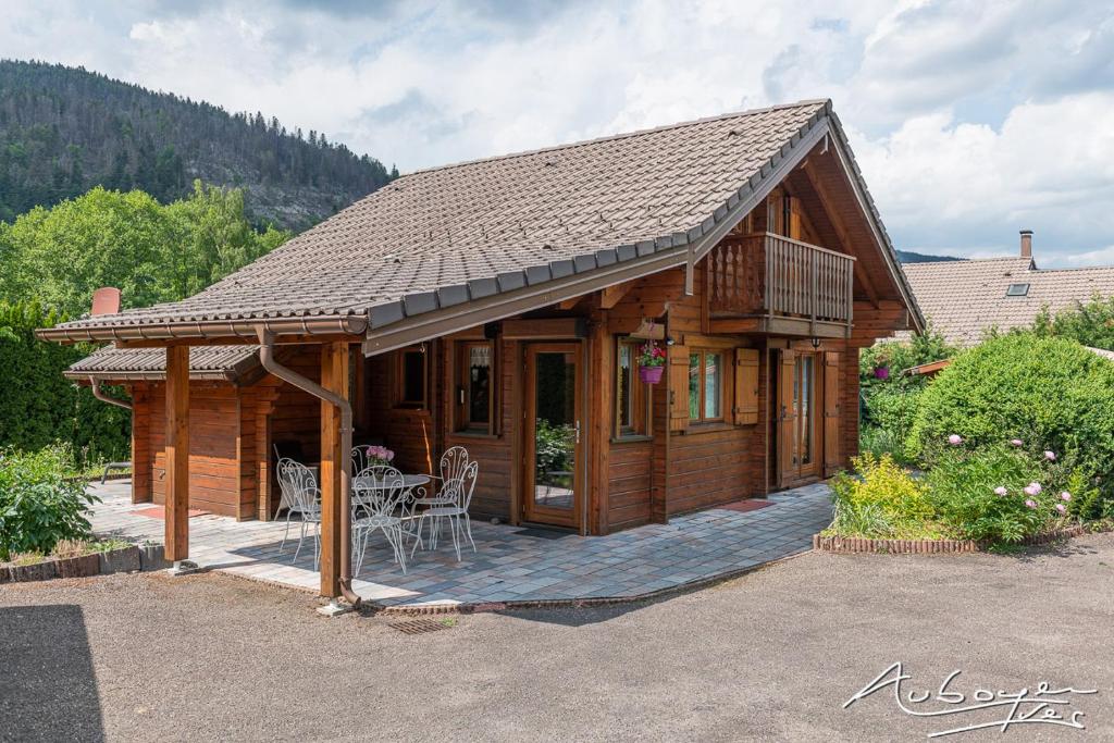 domek z bali ze stołem i krzesłami przed nim w obiekcie Chalet La Calougeotte, jardin, spa et sauna privés w mieście Le Ménil