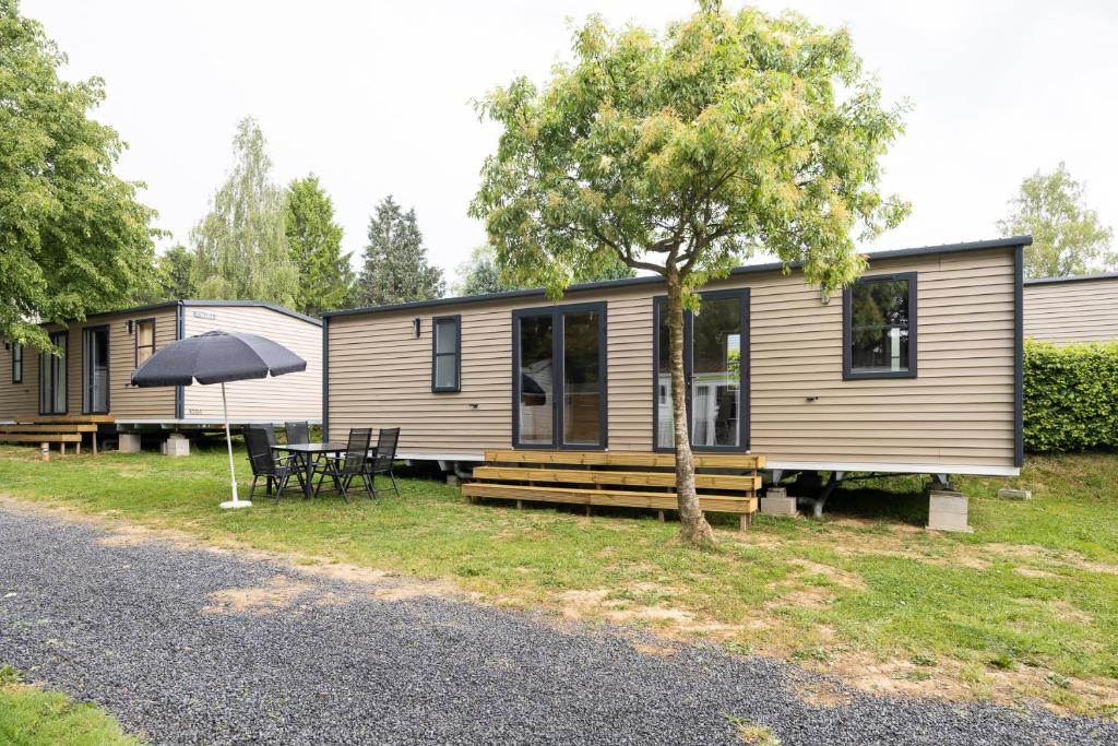 een stacaravan met een tafel en een paraplu bij ArdenParks Petite Suisse in Dochamps