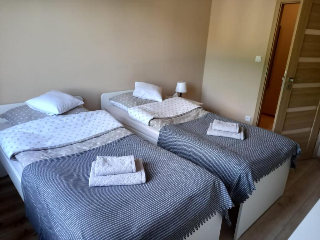 two beds in a room with towels on them at Apartament Górski in Szczytna