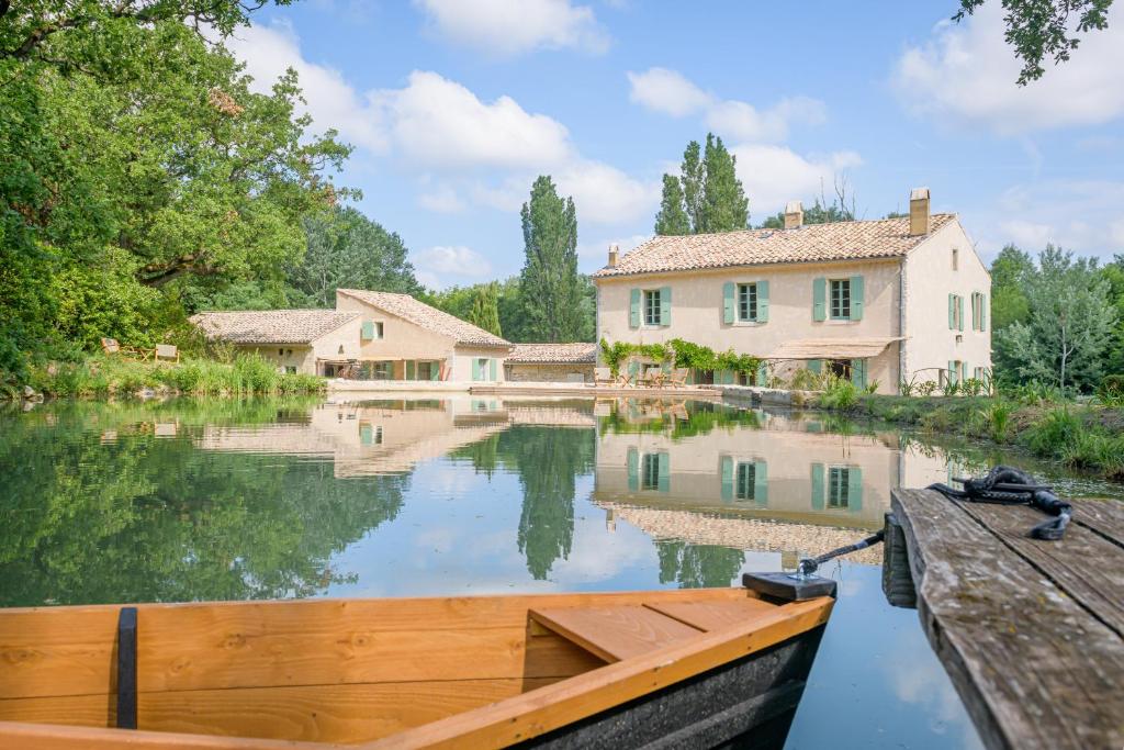 a house on a river with a boat in it at Le Moulin Dumas in Grignan