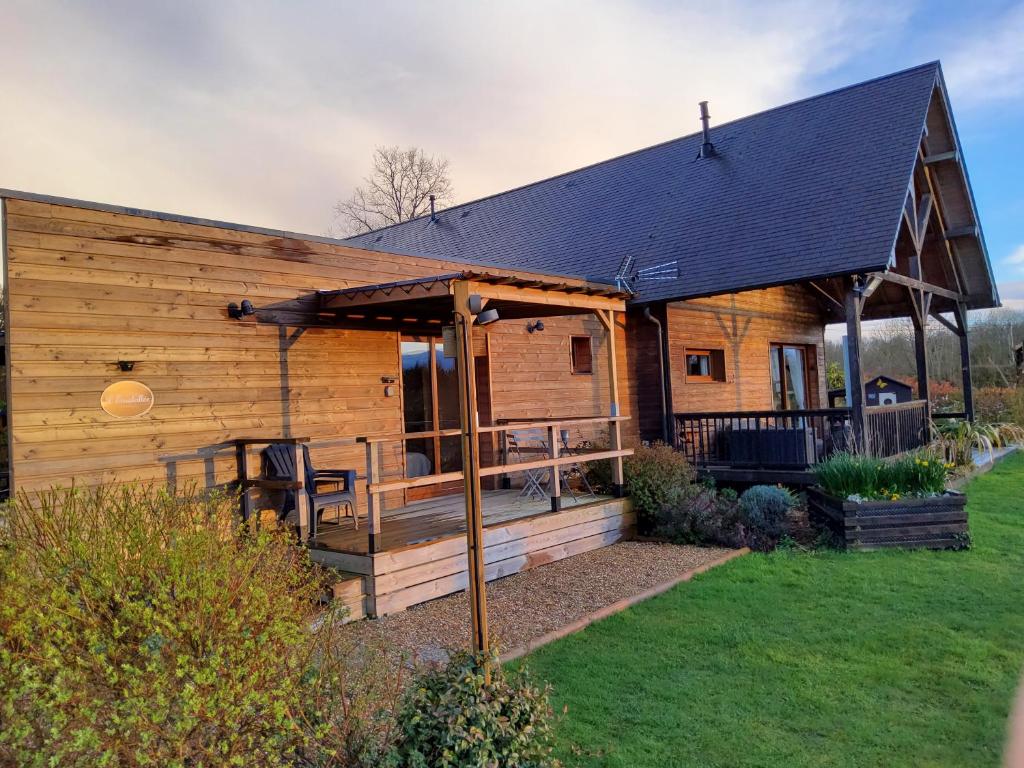 a log cabin with a porch and a deck at L' Ensoleillée Au Doux Refuge in Cordebugle