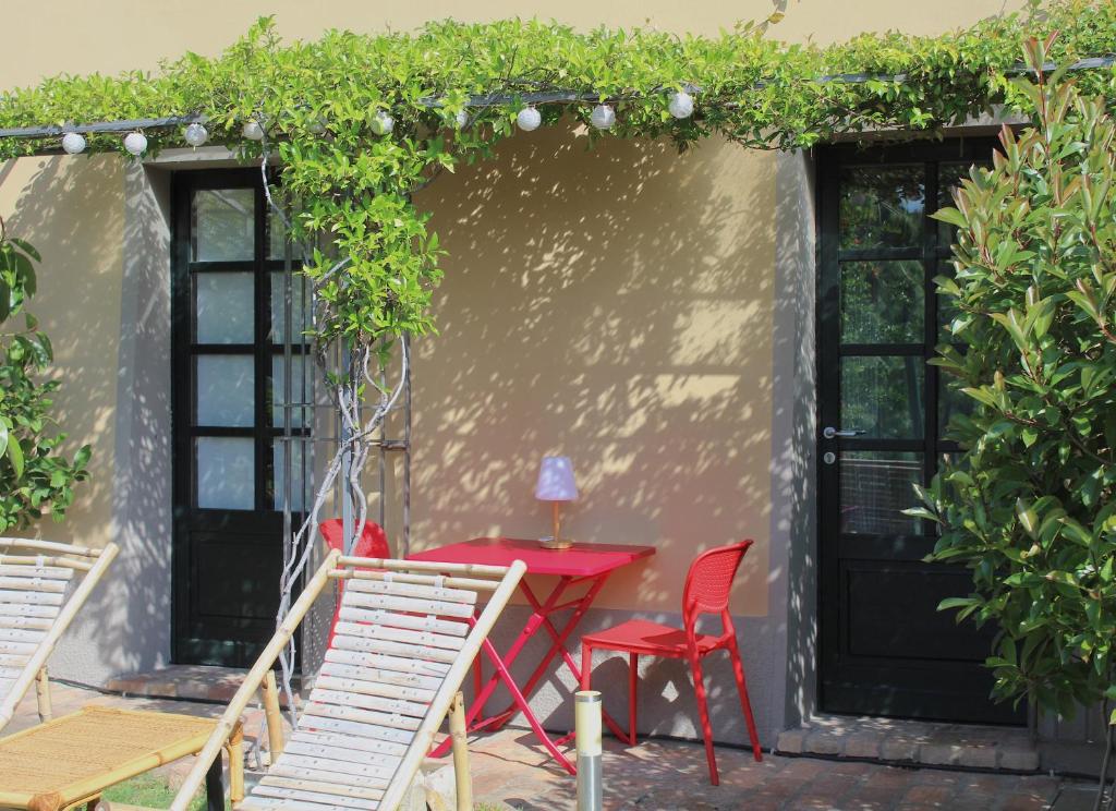 a patio with a red table and chairs and vines at AMAZING LANGHE AND MONFERRATO | House with garden in Calamandrana