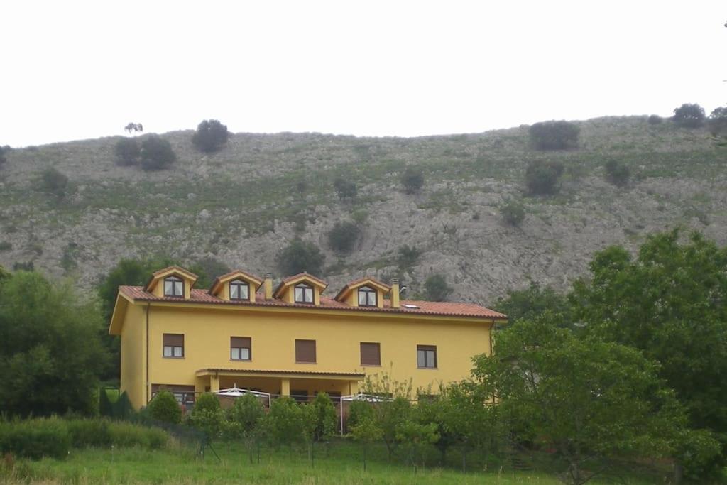ein gelbes Haus mit einem Berg im Hintergrund in der Unterkunft Viviendas Vacacionales Beni II in Llanes