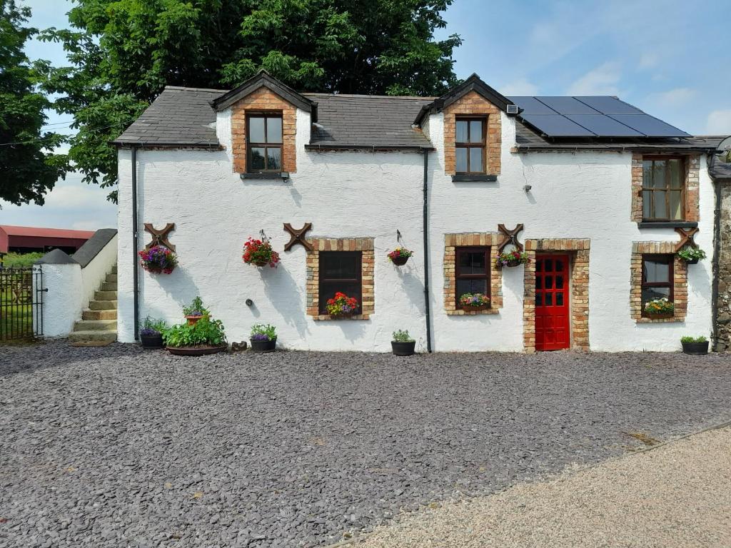 a white house with a red door and windows at Moira Barn At Berwickhall in Moira