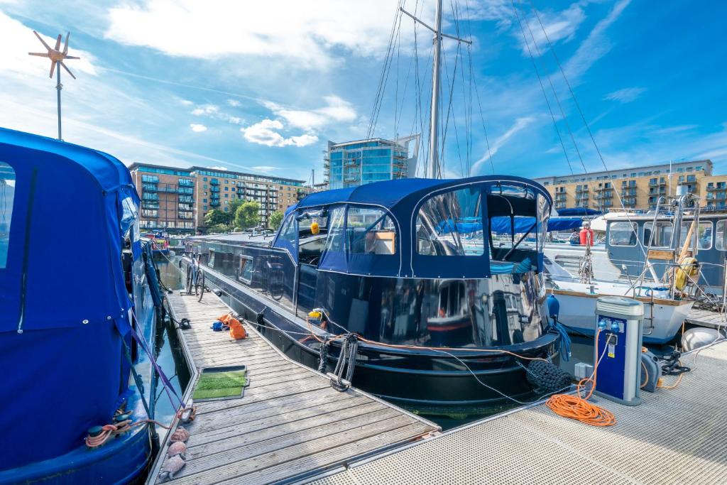 a blue boat is docked at a dock at ALTIDO Stylish barge near Canary Wharf in London