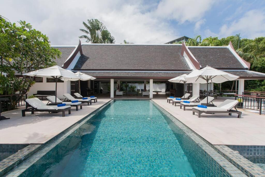 a swimming pool with lounge chairs and umbrellas at Katamanda - Villa Katamalee Private Pool near Kata Noi Beach in Kata Beach