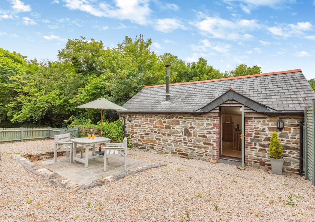 a stone cottage with a table and an umbrella at The Hayloft Dunmere in Bodmin