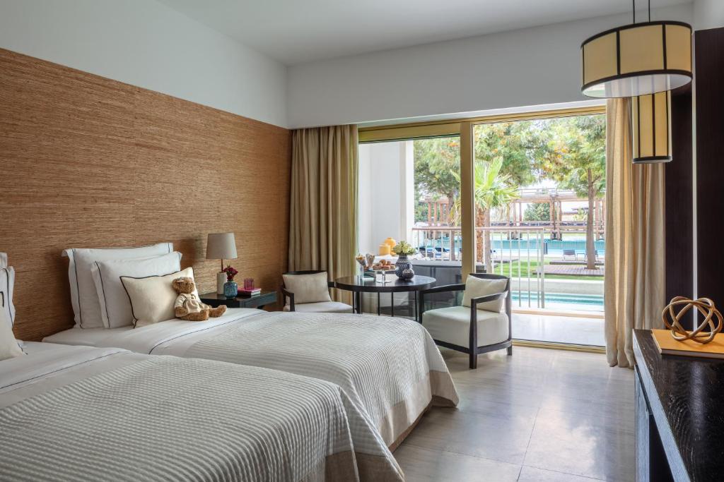 a hotel room with a bed and a desk and a large window at Anantara Vilamoura Family Friendly in Vilamoura