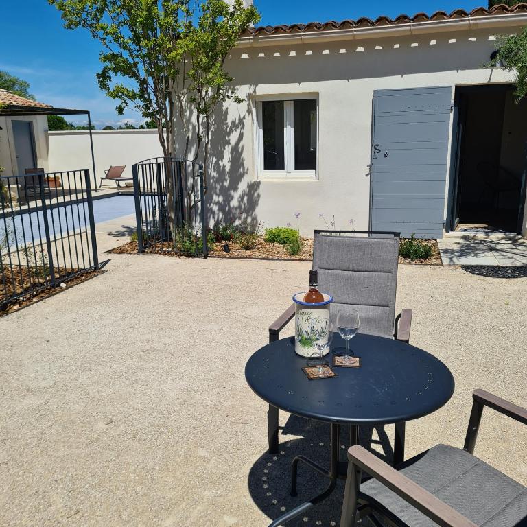 une table et une chaise avec un verre de vin dessus dans l'établissement Très joli mazet Piscine privée Beau jardin clôturé Entièrement privatisé 5' à pied du centre, à Saint-Rémy-de-Provence