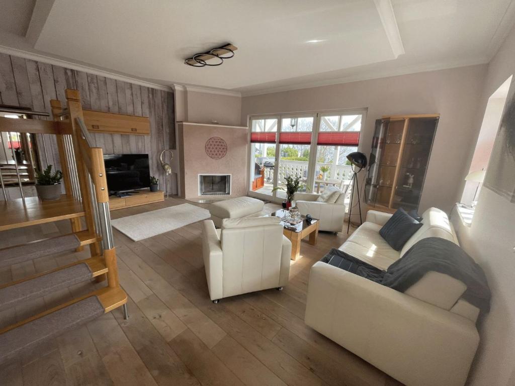 a living room with white furniture and a staircase at Villa Seestern - Ferienhaus mit Meerblick in Sassnitz