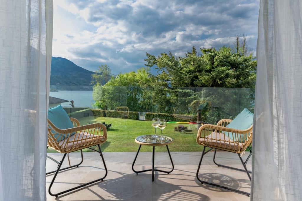 un patio con 2 sillas, una mesa y una ventana en Casa al Lago di TSS' - Ampio Giardino Fronte al Lago - Perfetto per Famiglie e Gruppi a Calceranica al Lago en Calceranica al Lago