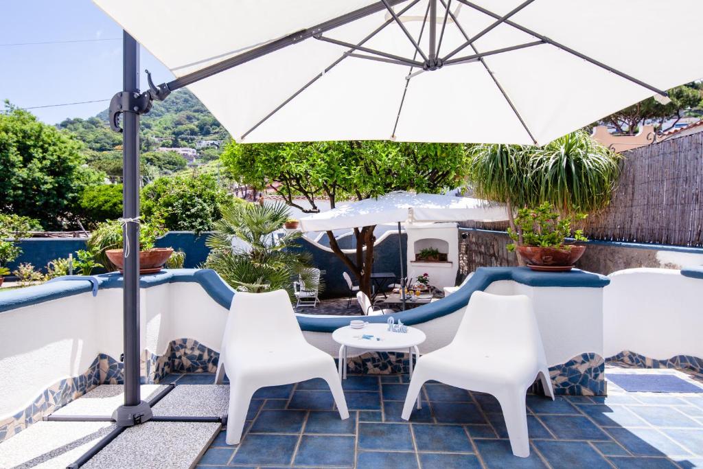 a patio with white chairs and an umbrella at BnB Le Isole in Ischia