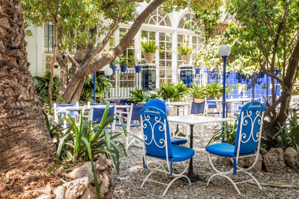 a group of blue chairs and a table in a garden at Hotel Medium Romantic in Sitges
