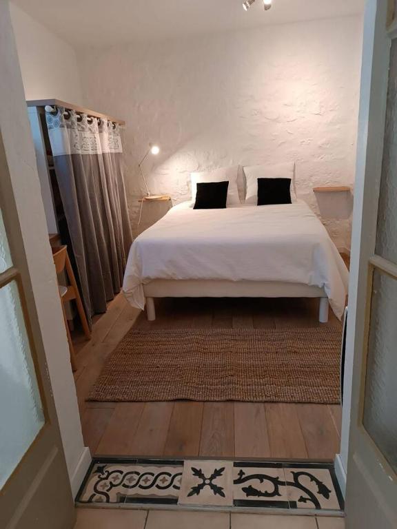 - une chambre avec un lit blanc et des oreillers noirs dans l'établissement Cosy appartement intra-muros, à Avignon