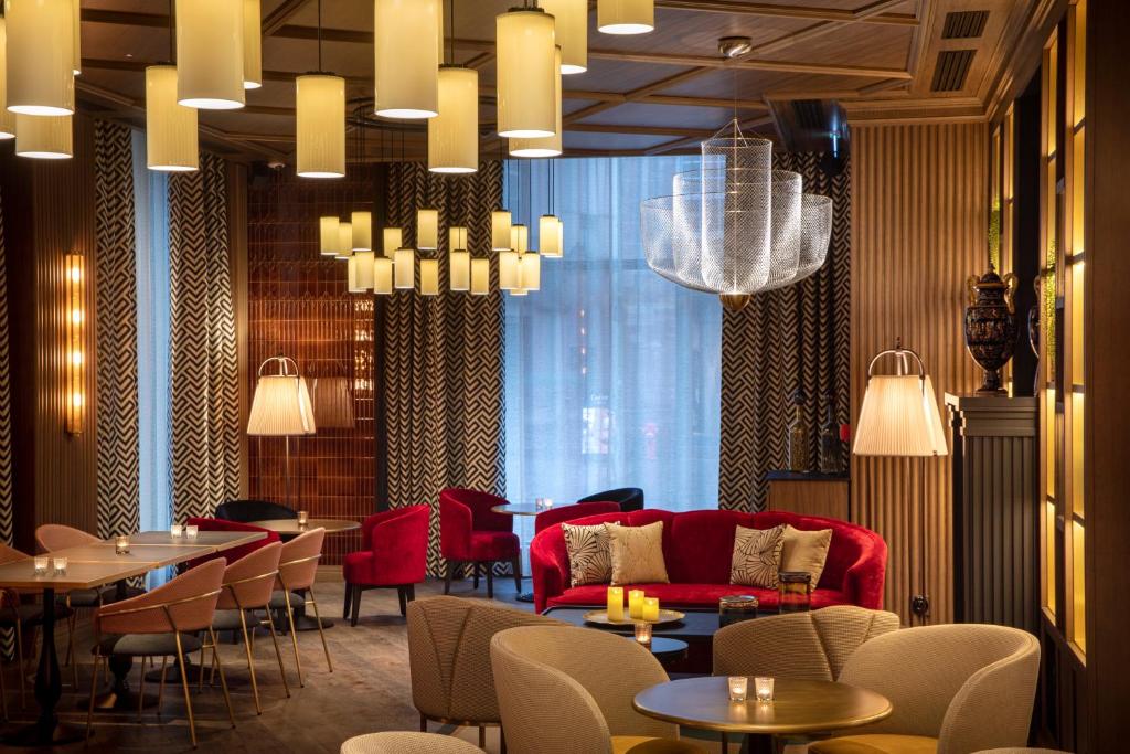 a restaurant with a red couch and tables and chairs at Maison Rouge Strasbourg Hotel & Spa, Autograph Collection in Strasbourg