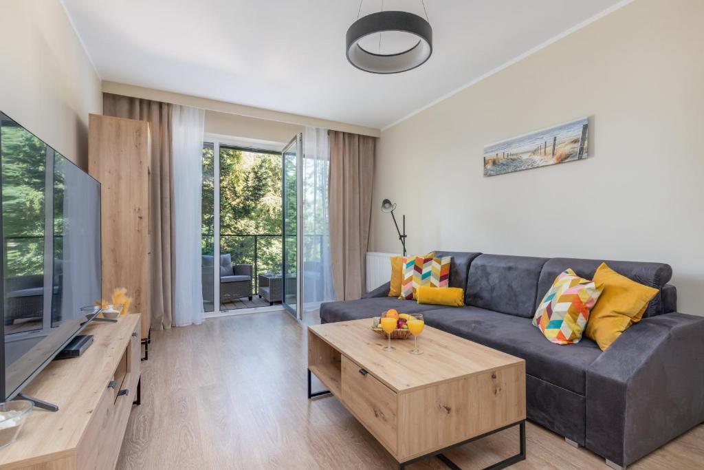 a living room with a couch and a table at Wellness Resort & SPA Dziwnów Apartments with Parking by Renters in Dziwnów