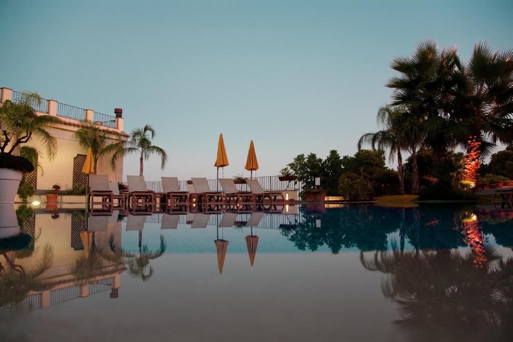 a pool with chairs and umbrellas in a resort at Best Western Hotel Santa Caterina in Acireale