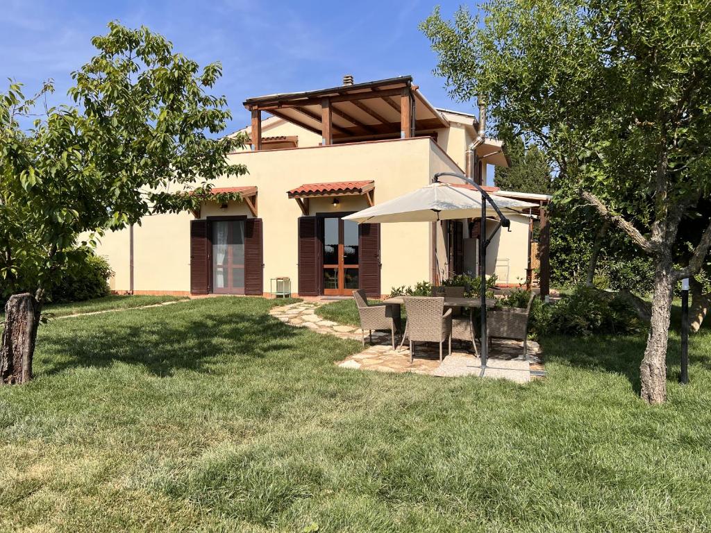 a house with a table and chairs and an umbrella at Casale Gemma Solaris in Marsiliana