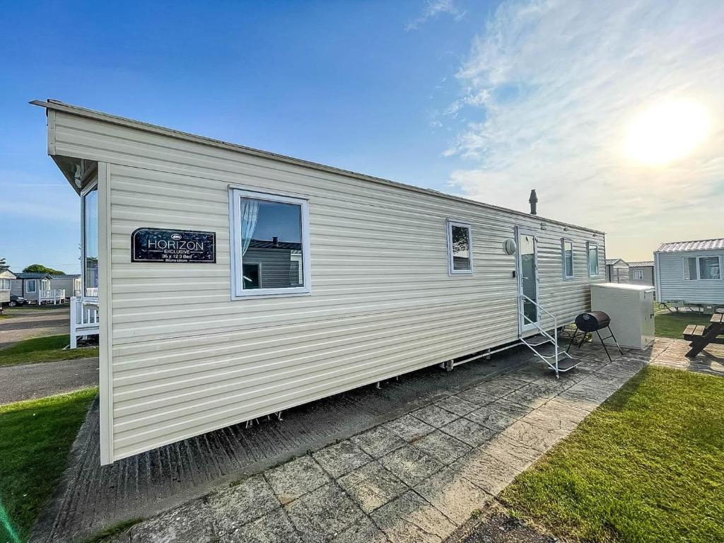 a white tiny house with a window and a patio at Superb 8 Berth Caravan At Caister Beach In Norfolk Ref 30073f in Great Yarmouth