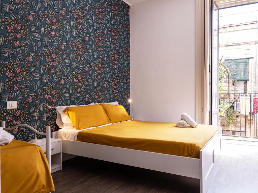 sypialnia z łóżkiem i ścianą ozdobioną tapetą w kwiaty w obiekcie B&B Università w Katanii
