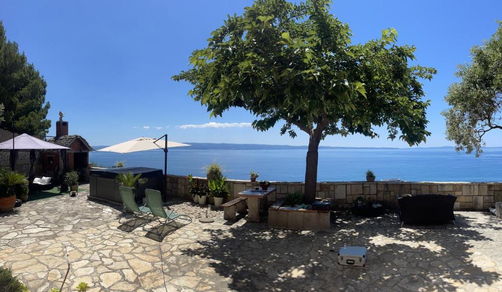 a patio with a tree and the ocean in the background at Super Horizont beach house-FREE PARKING AND JACCUZZI in Split