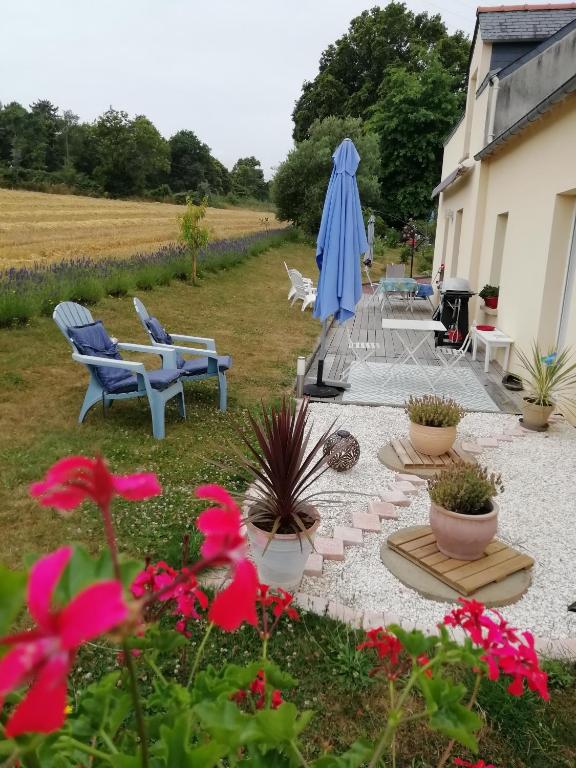 une terrasse avec des chaises, un parasol bleu et des fleurs dans l'établissement Kerlan 5, à Béganne