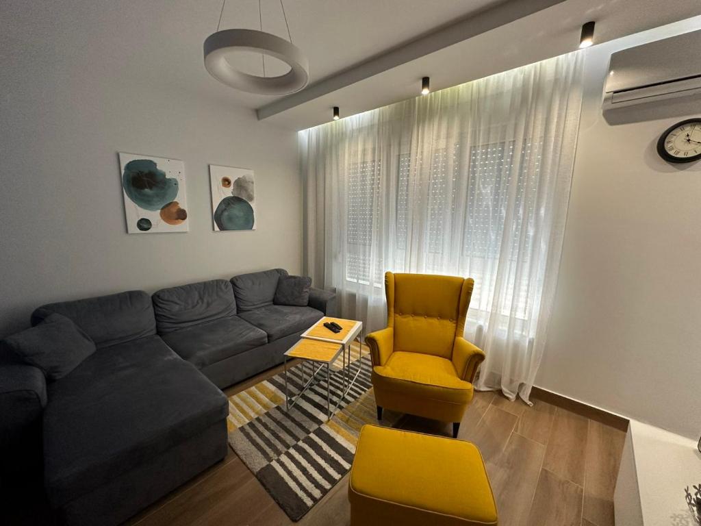 sala de estar con sofá y silla amarilla en GOX Apartman, en Subotica