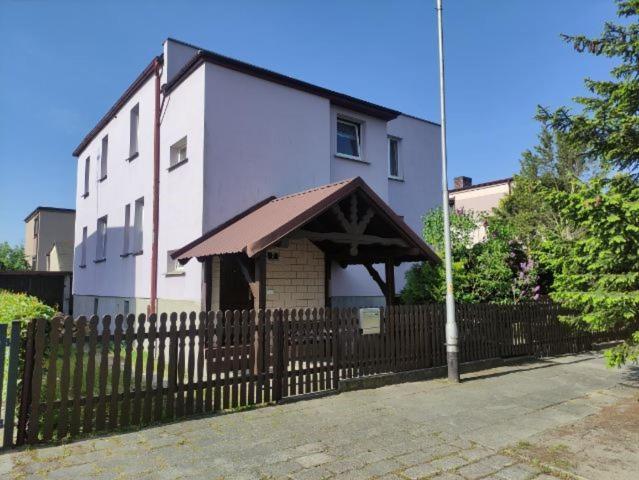 a white building with a wooden fence next to a house at Pod Modrzewiem ul Modrzewiowa 7 in Milicz
