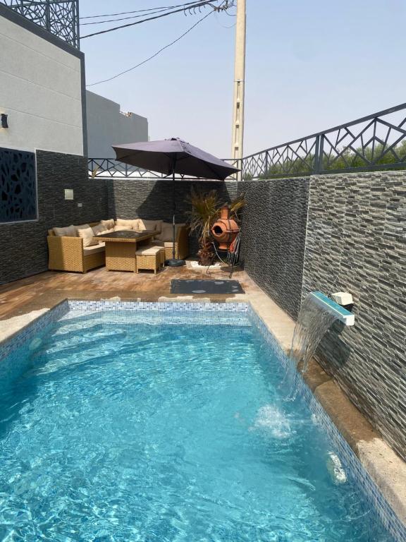 a swimming pool in front of a brick wall with an umbrella at Villa Aziza piscine privée in Oujda