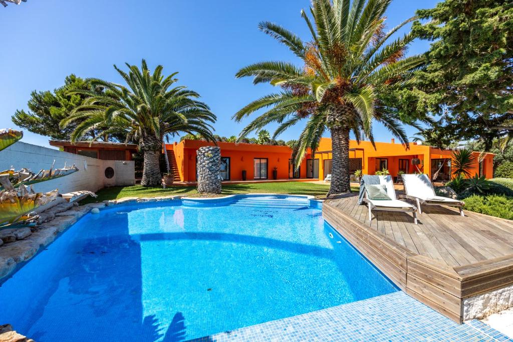 a swimming pool with palm trees and a house at Unique Villa -1 km to Beach, private Natural pool, Tennis Court & Jumping Mat in Sagres