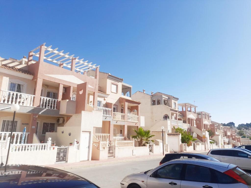 een rij huizen met auto's voor hen geparkeerd bij Villa Casa Max - duplex-apartment in Villamartin Golf Resort in Villamartin