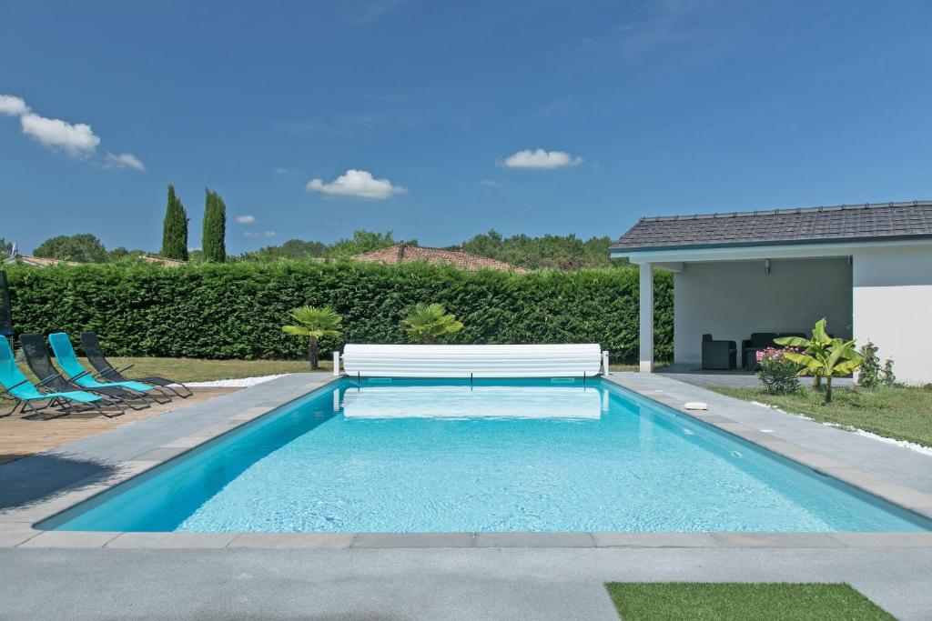 una piscina con un banco en un patio en Villa Blanca - Maison climatisée piscine privée, en Saint-Selve