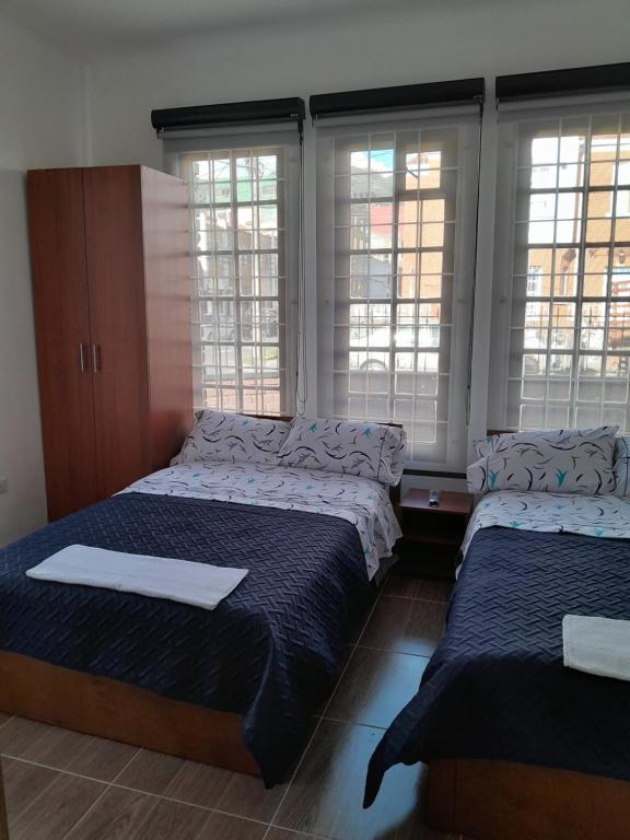 2 Betten in einem Zimmer mit Fenstern und Fensterscheiben in der Unterkunft Casa Hotel Palermo 49 in Bogotá