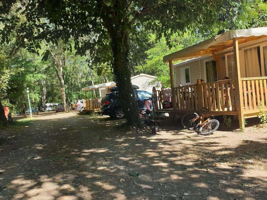 uma casa com uma bicicleta estacionada ao lado de uma árvore em Camping Paradis Bellerive em Montfrin