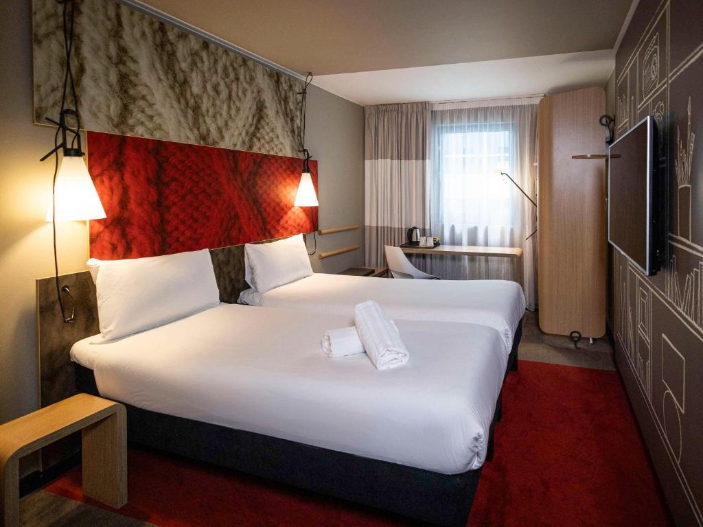 a hotel room with a large bed with white sheets at ibis London City - Shoreditch in London