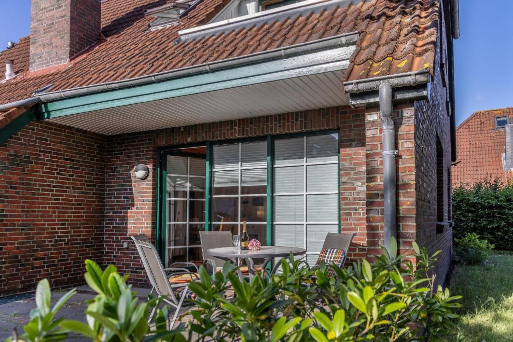 a patio with a table and chairs in front of a brick house at 50043... in Carolinensiel
