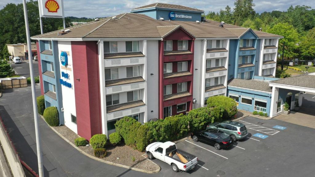 奧斯威戈湖的住宿－Best Western Lake Oswego Hotel & Suites，停车场内有车辆停放的公寓大楼