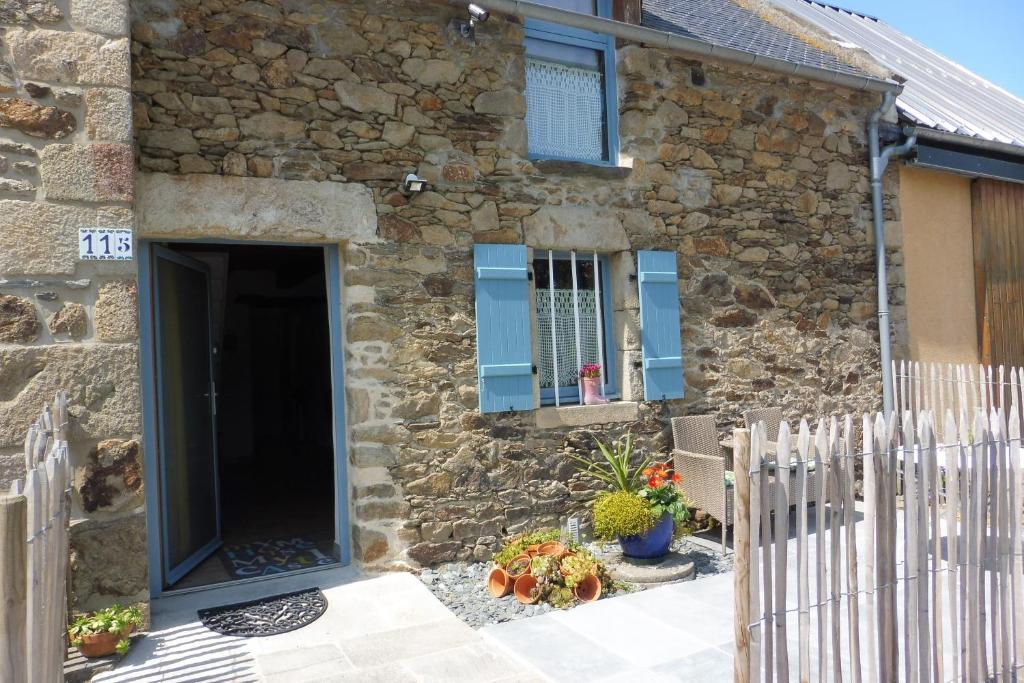 une maison en pierre avec des fenêtres bleues et un portail dans l'établissement Gîtes du Guébriand, à Saint-Lormel