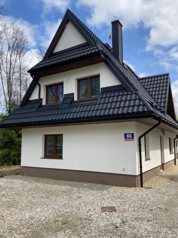 ein weißes Haus mit schwarzem Dach in der Unterkunft Domki nad potokiem in Białka Tatrzańska