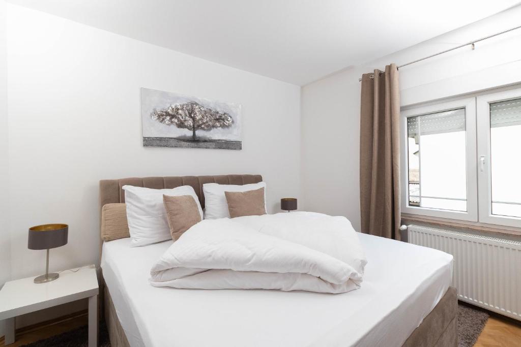 a bedroom with a white bed with a tree on the wall at Vila Maria in Vinkovci