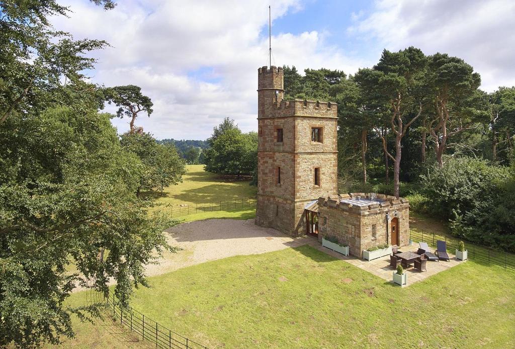 an old stone tower in a field with a picnic table at Knoll Tower in Shifnal