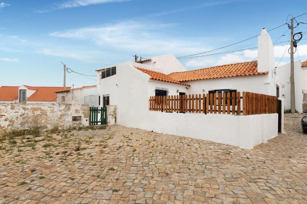 Casa blanca con puerta de madera y entrada de piedra en Casa Sol e Mar, en Colares