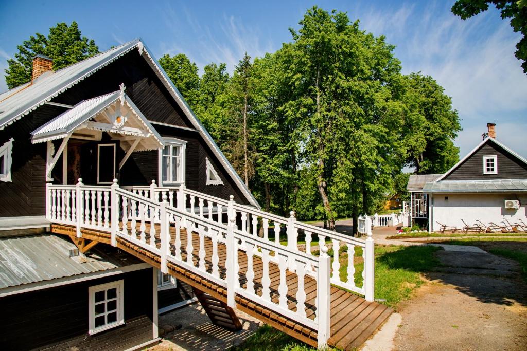 une maison avec un escalier en bois menant à une terrasse couverte dans l'établissement Skiemonių Dvaras, à Skiemonys