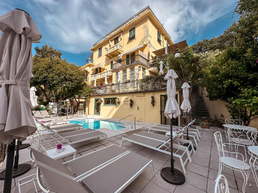 a hotel with a pool and chairs and a building at Hotel Villa Anita in Santa Margherita Ligure