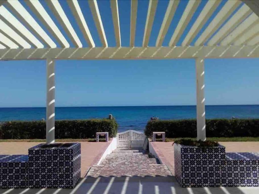 uma vista para a praia de debaixo de uma pérgola em Belle maison en face de la mer em El Maamoura