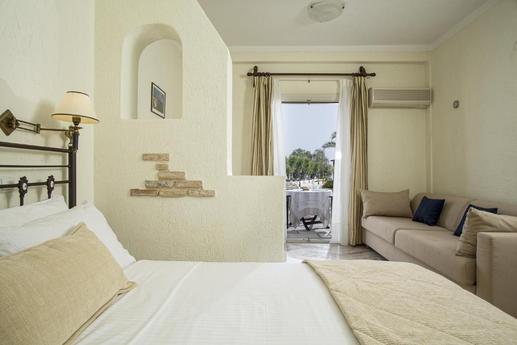 a bedroom with a bed and a living room with a couch at Contaratos Beach Hotel in Naousa