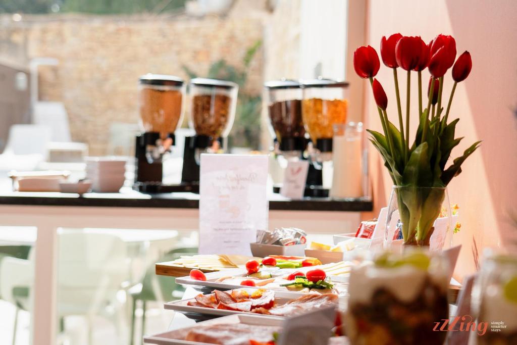 a table with plates of food and flowers and drinks at Spinola Stays in St. Julianʼs