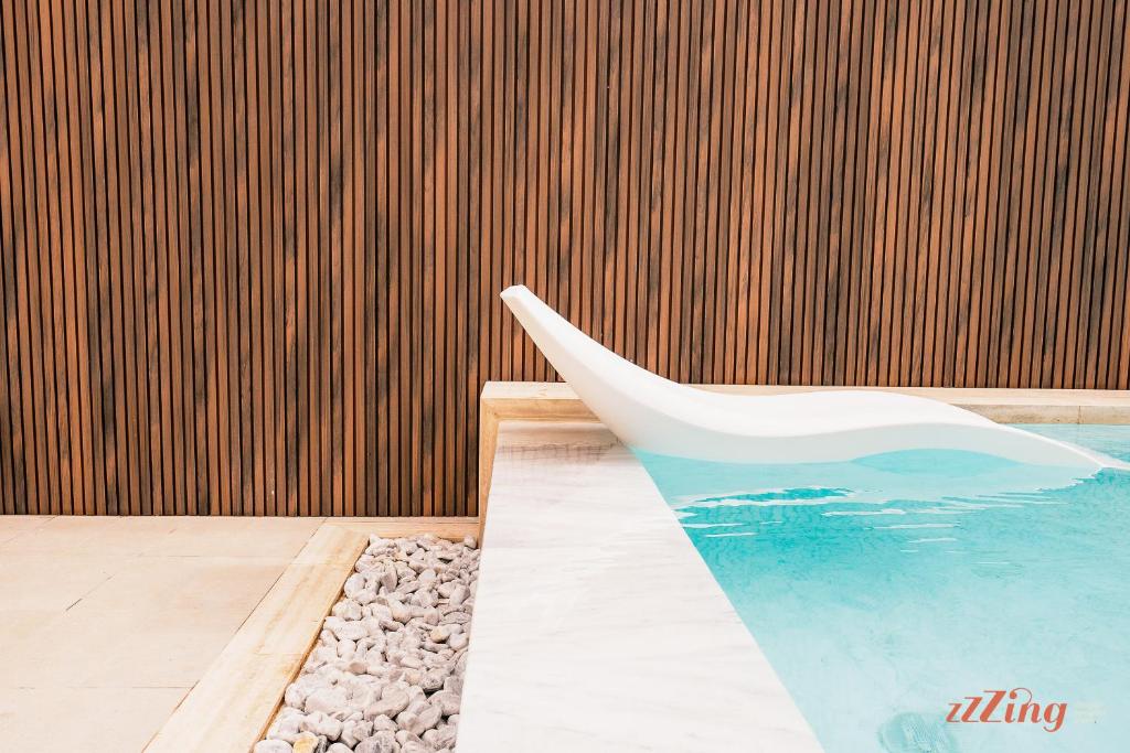 a white chair sitting next to a swimming pool at Spinola Stays in St. Julianʼs